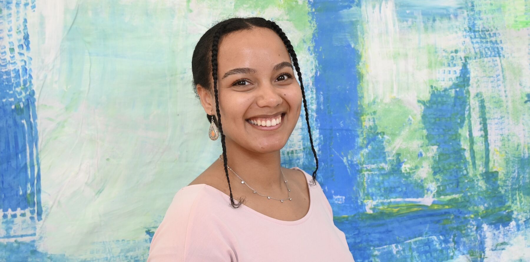 Profilbild von Frau Rosario vor einem blaugrünen Hintergrund