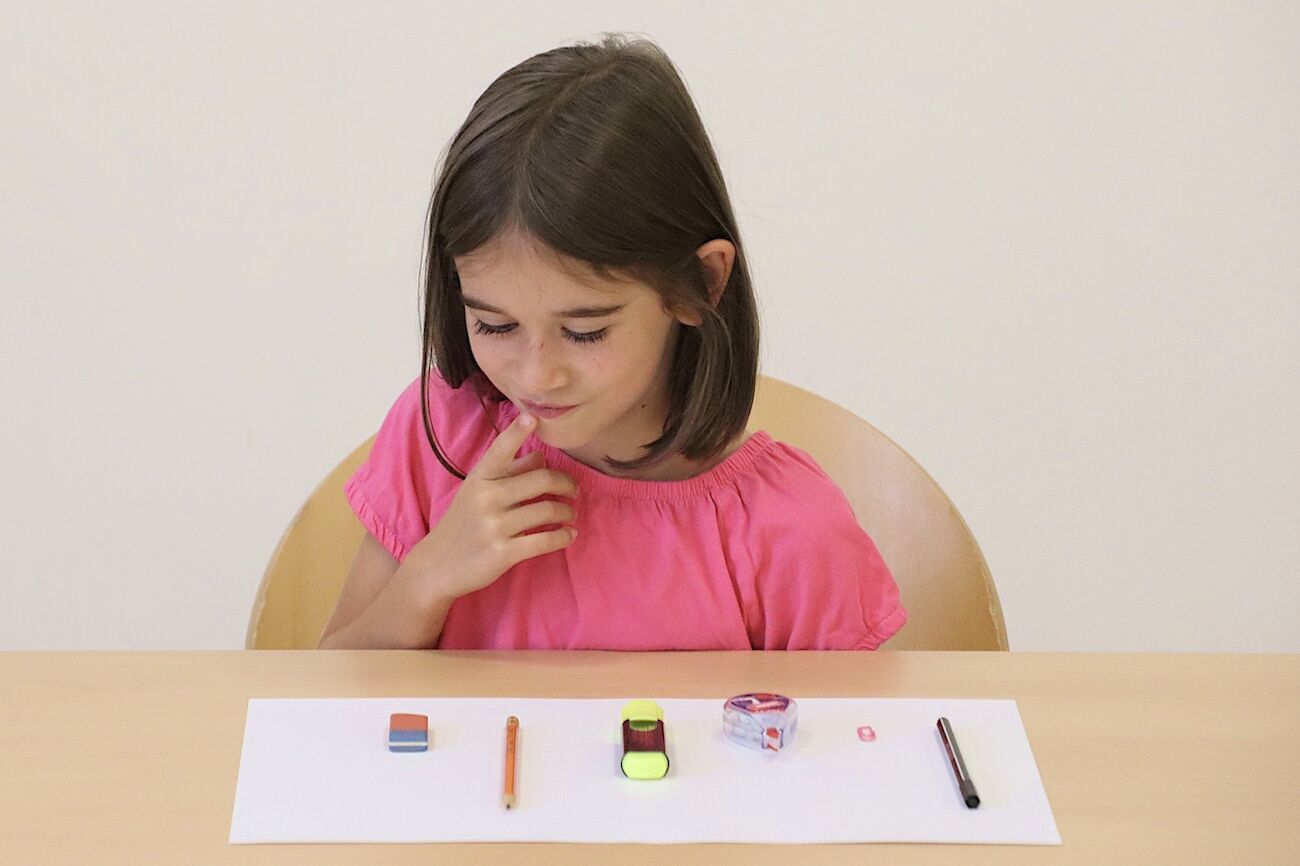 Ein Schulkind sitzt am Tisch und löst eine mathematische Aufgabe.