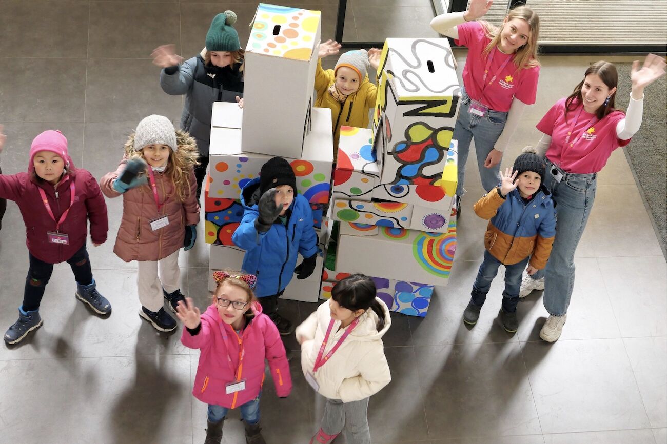 Kinder mit Studierenden in einem Kunstfoyer