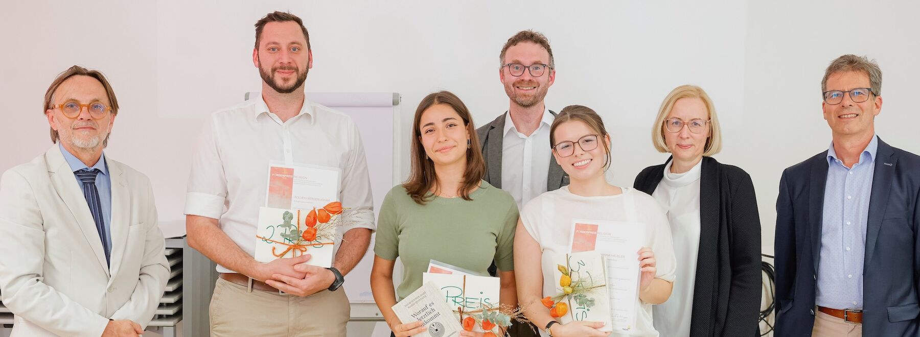 Gruppenbild: 3 Preisträger*innen mit Veranstalter*innen im Seminarraum