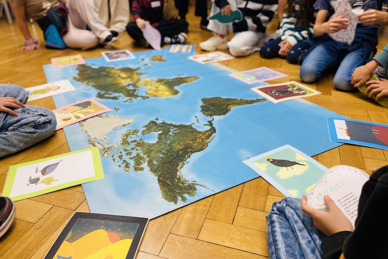 Kinder sitzen im Kreis um eine Weltkarte