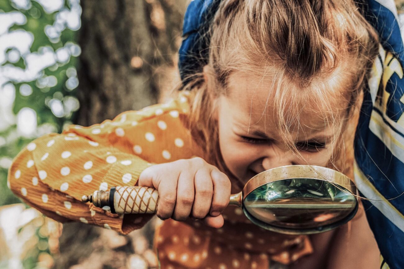 Sujetbild des Programmes: Ein Kind im Wald mit einer Lupe