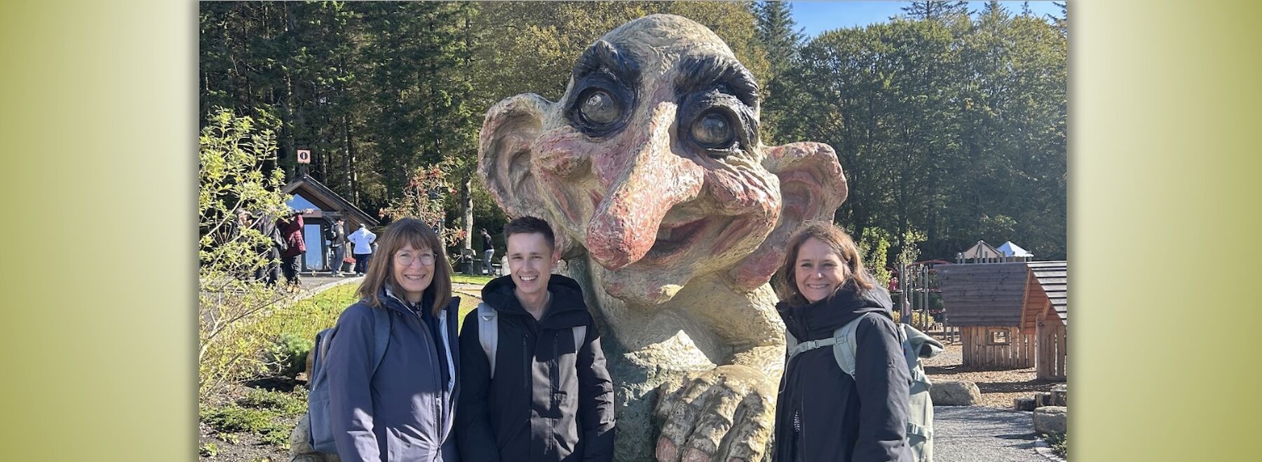 Drei Lehrende in Bergen (Outdoor) vor einer Figur