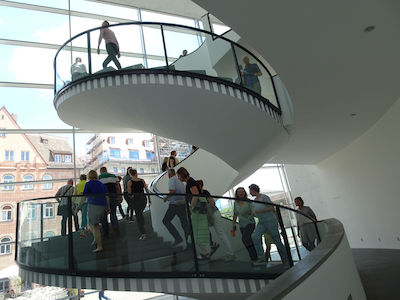 Menschen gehen in einem Gebäude eine moderne Wendeltreppe auf und ab.