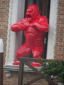 In einem Fenster steht eine rote, geometrische Gorillastatue und schlägt sich auf die Brust.