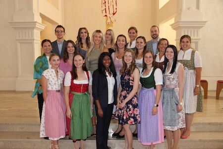 Eine Gruppe von Menschen posiert im Innenbereich, viele tragen traditionelle bayerische Kleidung.