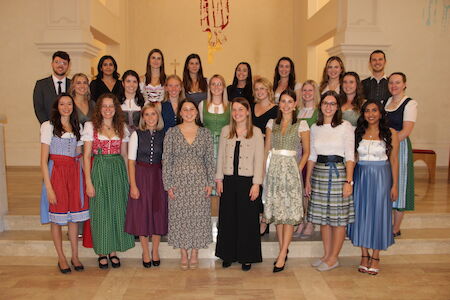 Eine Gruppe von Menschen, viele davon in traditioneller Kleidung, posiert gemeinsam im Innenbereich.