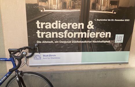 Plakat mit deutschem Text und davor geparktem Fahrrad.