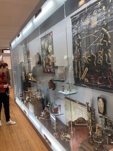Menschen betrachten medizinische Artefakte und anatomische Modelle in einer Museumsvitrine.