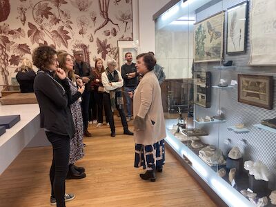 Eine Gruppe von Menschen schaut sich Museumsausstellungen an, während ein Führer mit ihnen spricht.