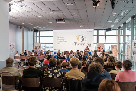 Personen, die an einer eTwinning-Veranstaltung in einem Konferenzraum mit großem Bildschirm teilnehmen.