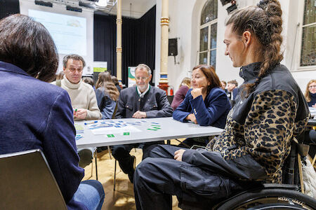 Bei einer Indoor-Veranstaltung sitzen vier Personen um einen Tisch und diskutieren.