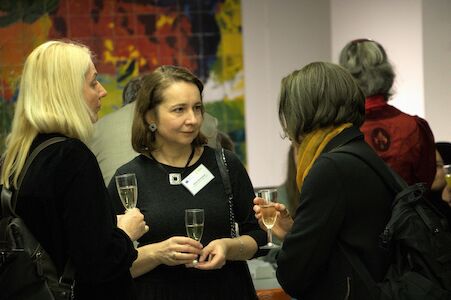 Drei Frauen unterhalten sich und halten Gläser bei einem geselligen Beisammensein oder einer Networking-Veranstaltung.