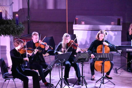 Vier Musiker spielen Streichinstrumente auf der Bühne, vor ihnen stehen Notenständer.