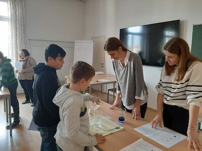 Kinder und Erwachsene führen gemeinsam in einem Klassenzimmer ein wissenschaftliches Experiment durch.