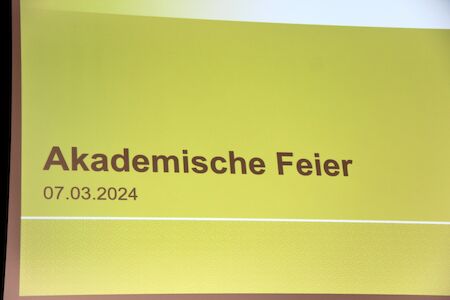 Gelbe Folie mit Text „Akademische Feier“ und Datum 07.03.2024 in deutscher Sprache.