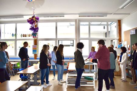 Eine Gruppe Erwachsener steht in einem hellen Klassenzimmer und unterhält sich.