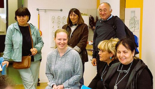 Sechs Erwachsene lächeln und posieren gemeinsam in einem hell erleuchteten Raum.