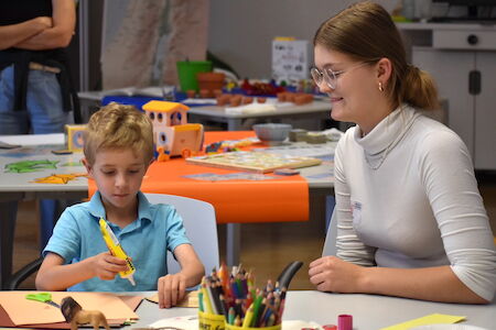 Junge Frau und Junge basteln gemeinsam an einem Tisch mit Kunstbedarf.