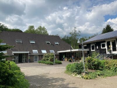 Zwei Gebäude mit schrägen Dächern und einem Innenhof unter einem bewölkten Himmel.