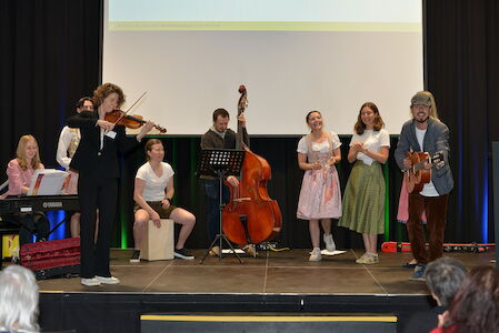 Eine Gruppe von Musikern und Sängern tritt mit verschiedenen Instrumenten auf der Bühne auf.