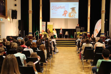 Publikum sieht sich in einem Auditorium eine Präsentation bei einer Preisverleihung für Kinder an.