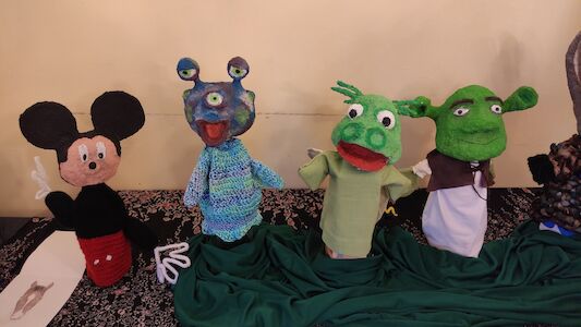 Ausgestellt sind vier bunte Handpuppen, darunter Mickey Mouse und Shrek.