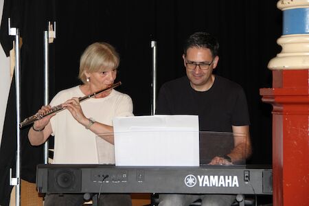 Eine Frau spielt Flöte und ein Mann spielt Keyboard zusammen auf der Bühne.