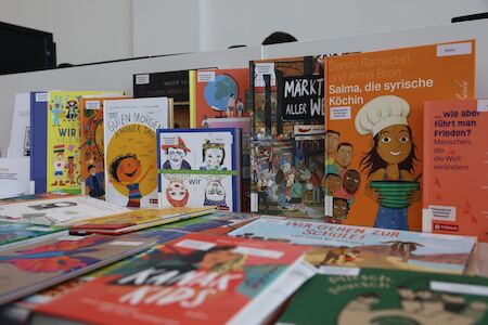 Kinderbücher mit bunten Einbänden werden bei einer Ausstellung auf einem Tisch ausgestellt.