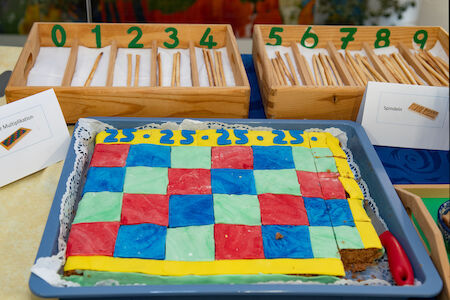 Bunt karierte Torte mit Zahlenstäben und Zählstäben im Hintergrund.