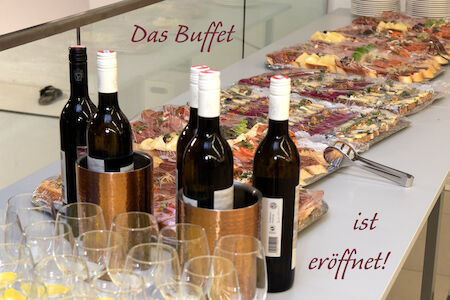 Ein Buffettisch mit Weinflaschen, Gläsern und verschiedenen Vorspeisen.