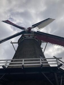 Untersicht einer traditionellen Windmühle mit bewölktem Himmel im Hintergrund.