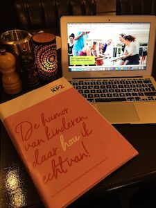 Ein rosa Ordner und ein Laptop auf einem Tisch neben einer Kerze und einer Pfeffermühle.