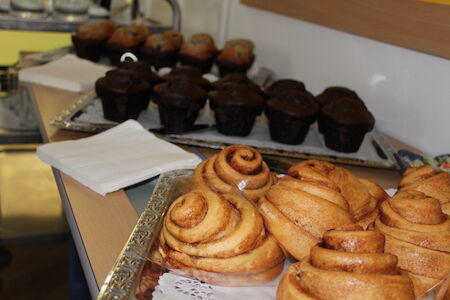 Zimtschnecken und Schokoladenmuffins auf Tabletts auf einem Tisch angeordnet.