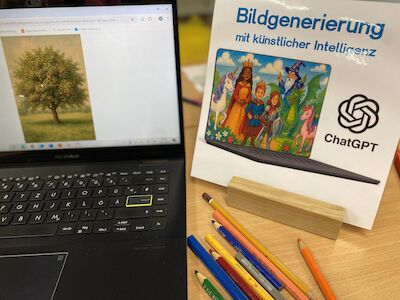 Ein Laptop und ein Schild zur KI-Bildgenerierung mit Buntstiften auf einem Schreibtisch.
