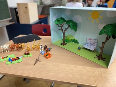 Diorama eines Parks mit Spielzeugtieren und Picknickartikeln auf einem Klassenzimmertisch.