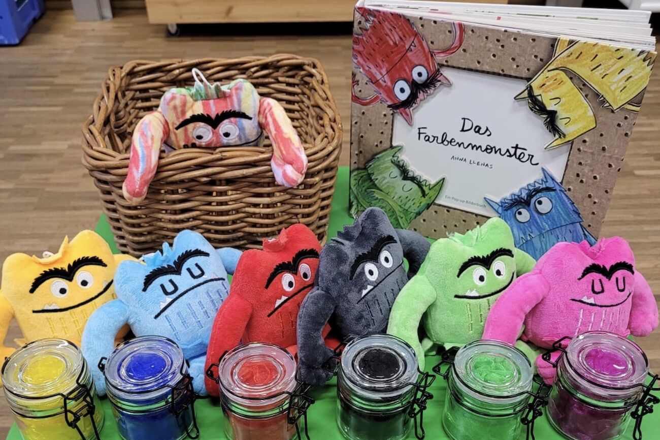Farbenmonster als Plüschtiere und das Buch auf einem Tisch